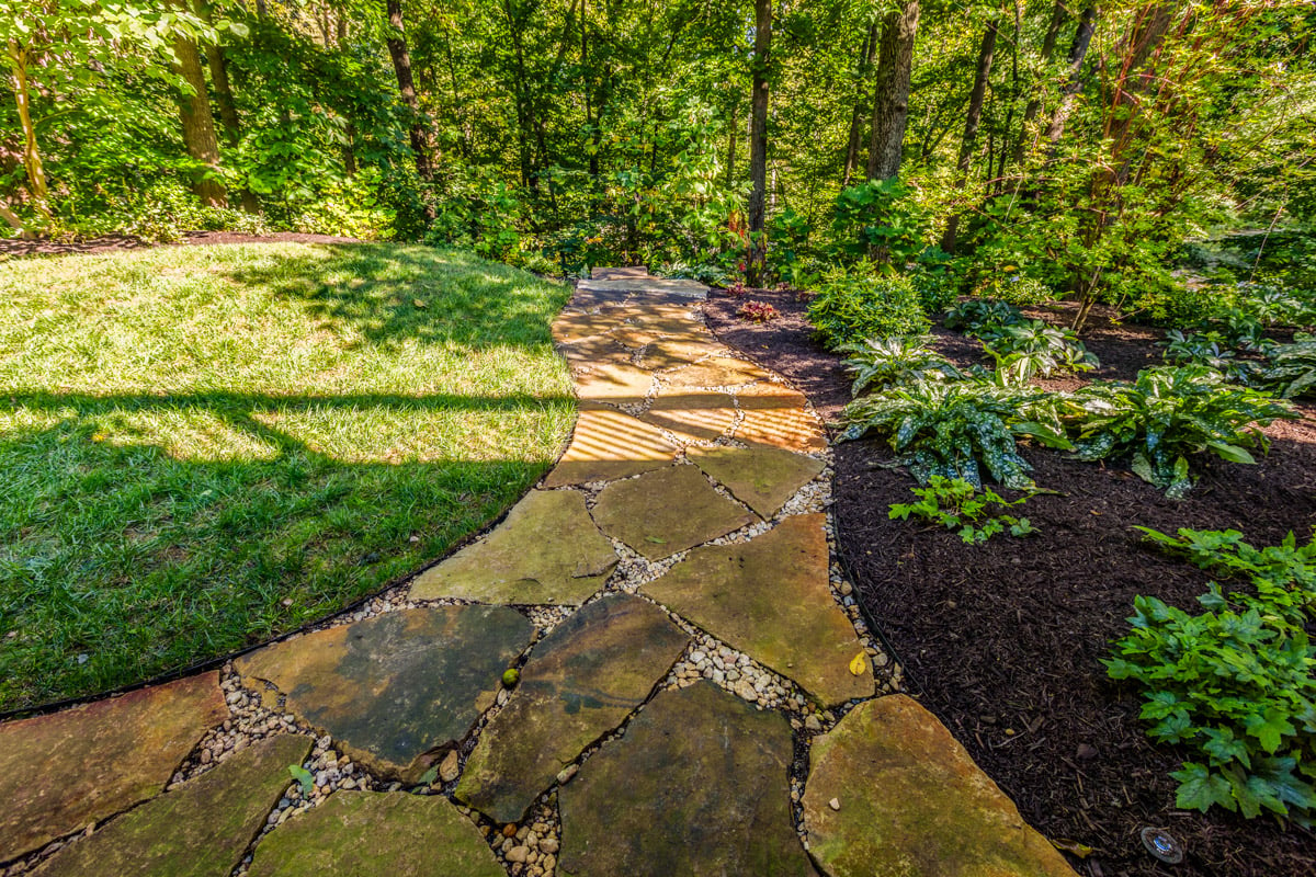 natural flagstone walkway between lawn and planting beds