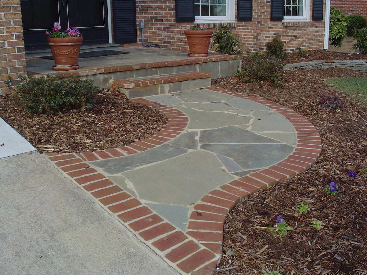 flagstone walkway with a brick border in a front yard planting bed